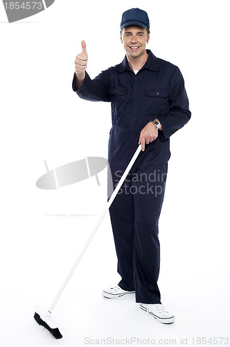 Image of Cleaning guy holding broom and showing thumbs up