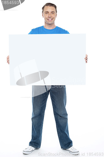 Image of Handsome casual guy holding blank ad board
