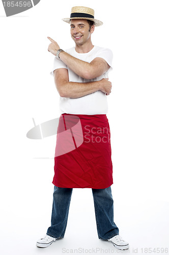Image of Man wearing a hat and apron pointing away