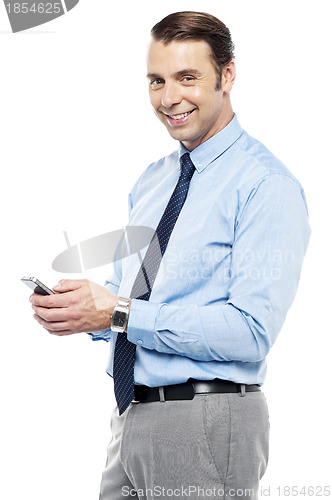 Image of Smiling young manger sending sms from phone