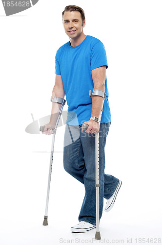 Image of Young man with crutches trying to walk