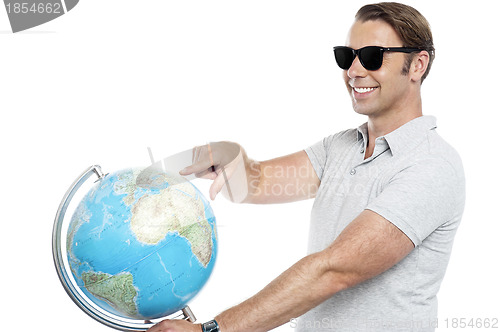 Image of Handsome guy in goggles pointing at globe