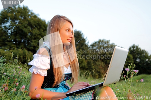 Image of Bavarian Girl with Laptop in a flowering meadow