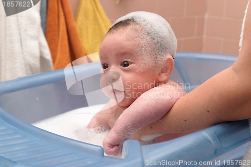 Image of Cute baby in a bathtub with foam cap on his head