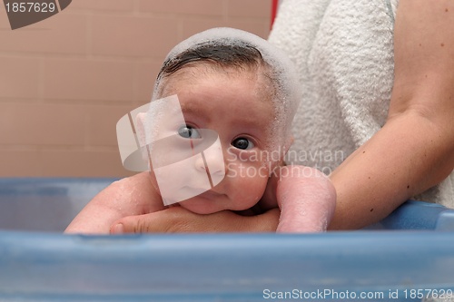 Image of Cute baby in a bathtub with foam cap on his head