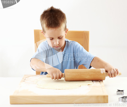 Image of Small boy rolling dough for cookies 