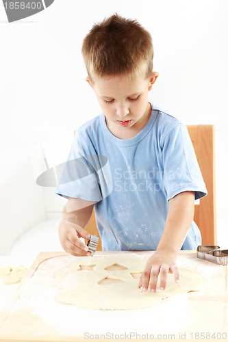 Image of Small boy cutting cookies
