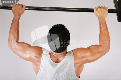 Image of Reaching Goal: Strong man doing pull-ups on a bar in a gym