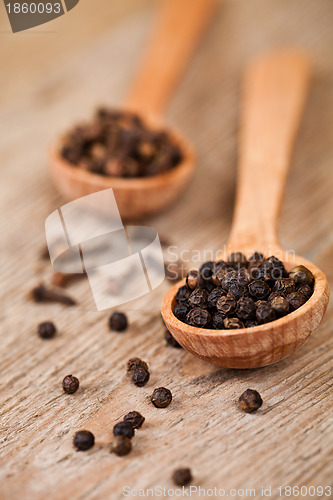 Image of black pepper and cloves in wooden spoons 