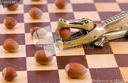 Image of Gold crocodile nut crush tool on chess board 