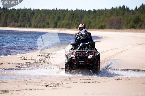 Image of two men riding all-terrain vehicle