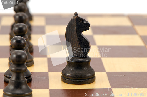 Image of Knight stand in front of all pawn chess line board 