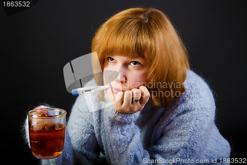 Image of sick girl with tea and a thermometer