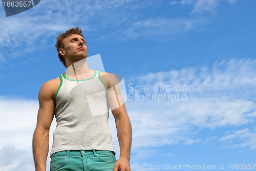 Image of Strong young man on blue sky background