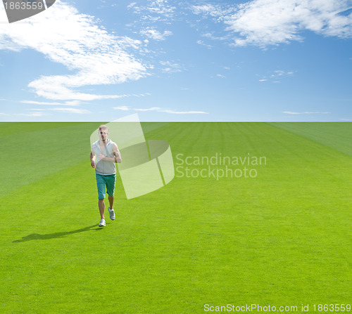 Image of Sporty young man running on green field