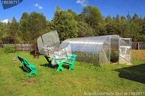 Image of garden furniture near plastic hothouse