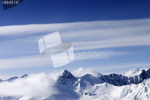 Image of High mountains in haze and blue sky with clouds