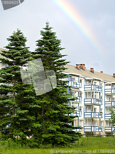 Image of Apartment building, spruce trees and rainbow