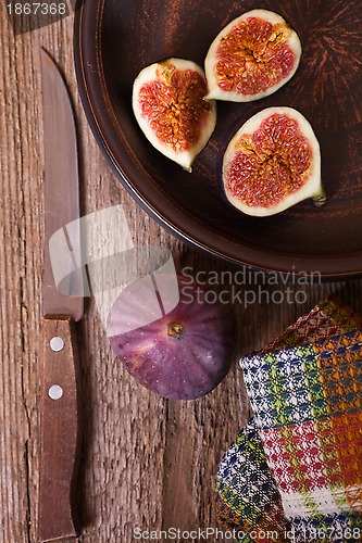 Image of  fresh figs in a plate, old knife and towel 