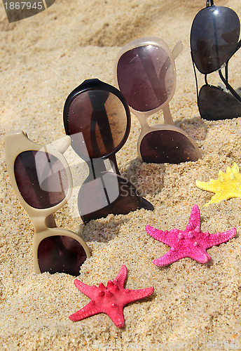 Image of Four pairs of sunglasses on the beach 