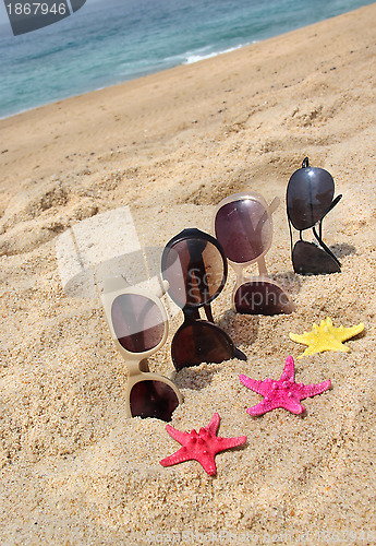 Image of Four pairs of sunglasses on the beach 