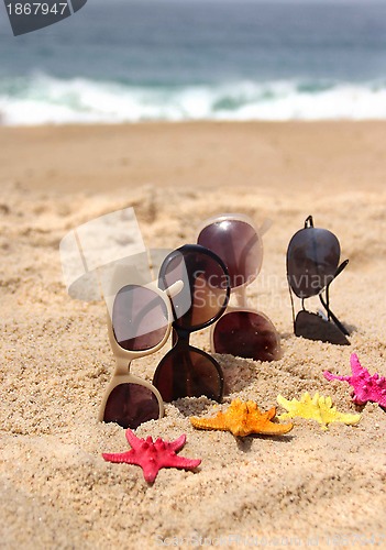 Image of Four pairs of sunglasses on the beach 