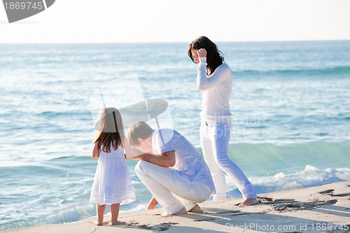 Image of happy young family with daughter on beach in summer