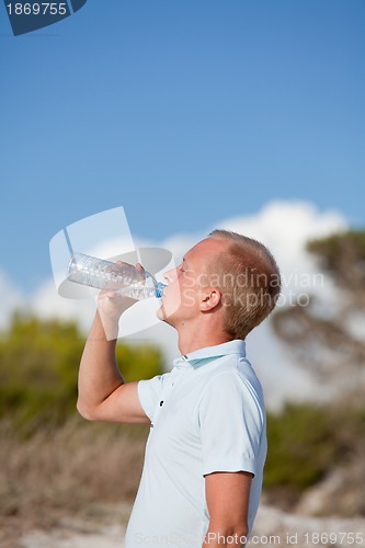 Image of young man ist drinking water summertime dune beach sky