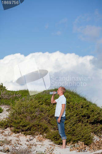 Image of young man ist drinking water summertime dune beach sky