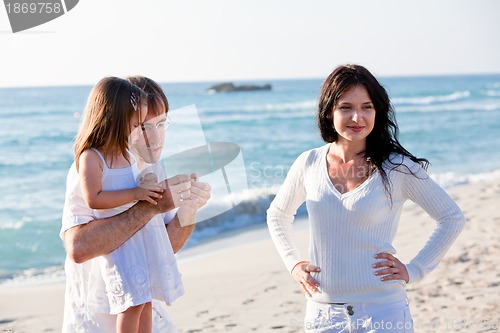 Image of happy young family with daughter on beach in summer