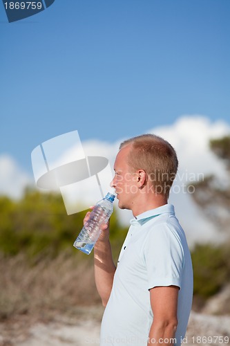 Image of young man ist drinking water summertime dune beach sky