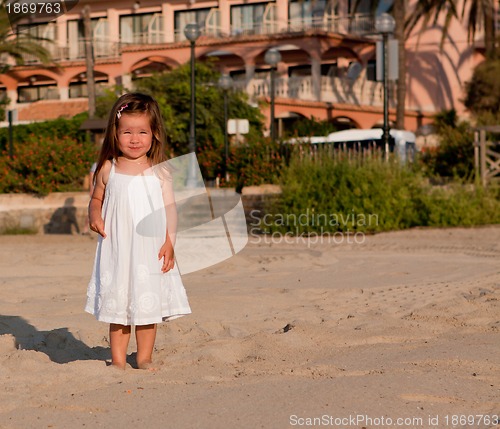 Image of little cute girl smiling playing on beach in summer