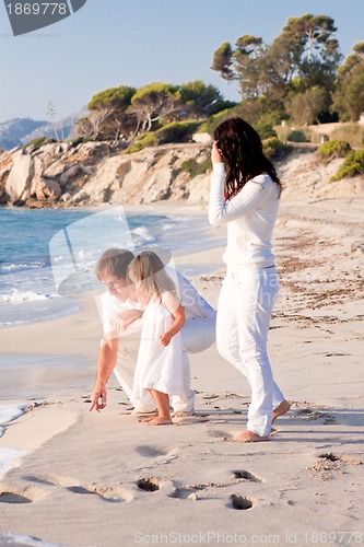 Image of happy young family with daughter on beach in summer