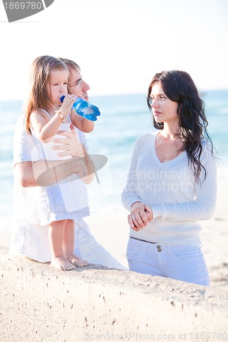 Image of happy young family with daughter on beach in summer