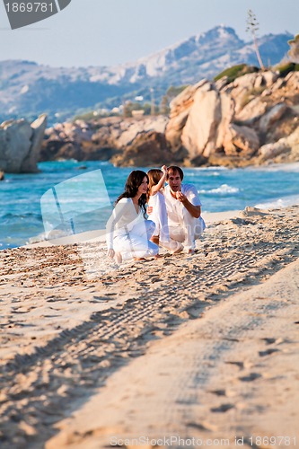 Image of happy young family with daughter on beach in summer