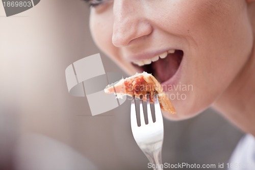 Image of young woman is eating a pizza in restaurant