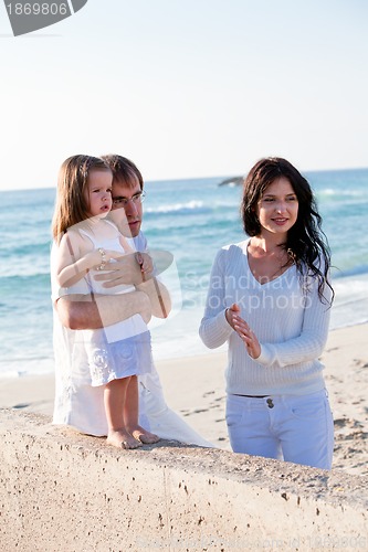Image of happy young family with daughter on beach in summer