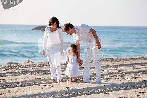 Image of happy young family with daughter on beach in summer