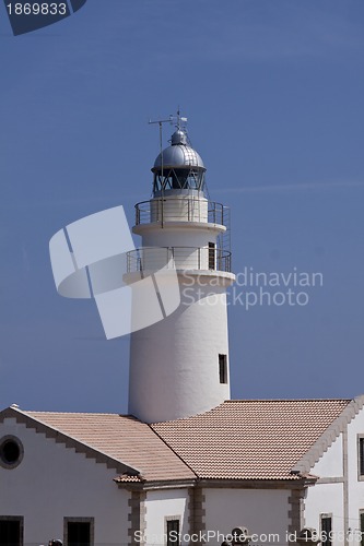 Image of white lighthouse on rocks in the sea ocean water sky blue