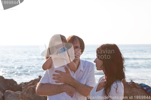 Image of happy young family with daughter on beach in summer