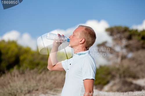 Image of young man ist drinking water summertime dune beach sky