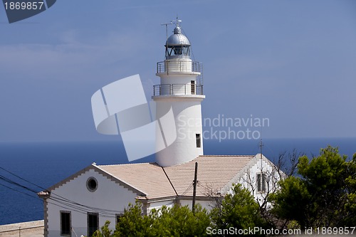 Image of white lighthouse on rocks in the sea ocean water sky blue