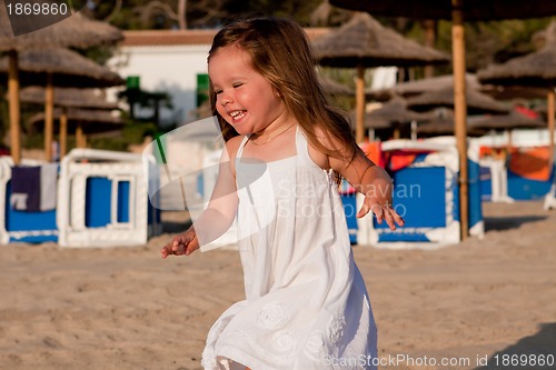 Image of little cute girl smiling playing on beach in summer