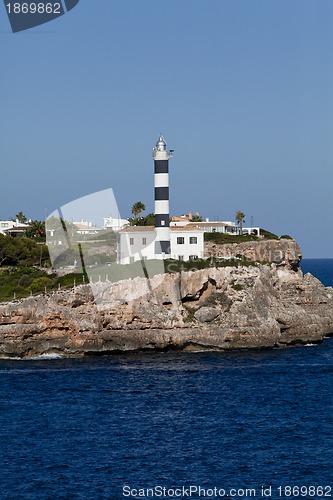 Image of white lighthouse on rocks in the sea ocean water sky blue