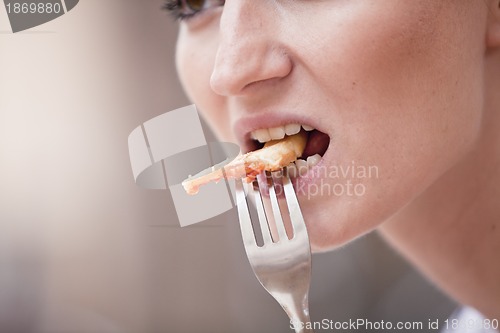 Image of young woman is eating a pizza in restaurant