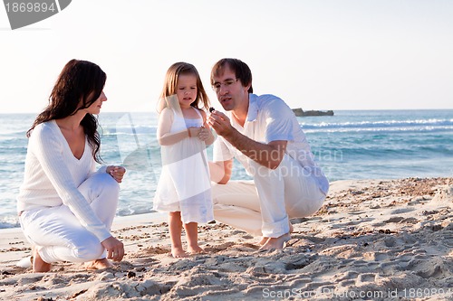Image of happy young family with daughter on beach in summer