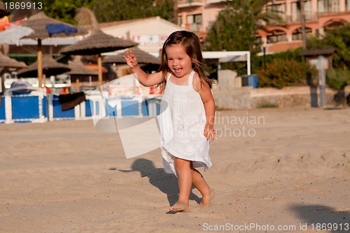Image of little cute girl smiling playing on beach in summer
