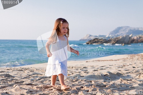 Image of little cute girl smiling playing on beach in summer