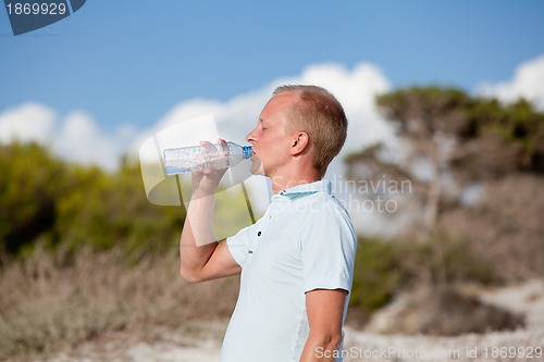 Image of young man ist drinking water summertime dune beach sky