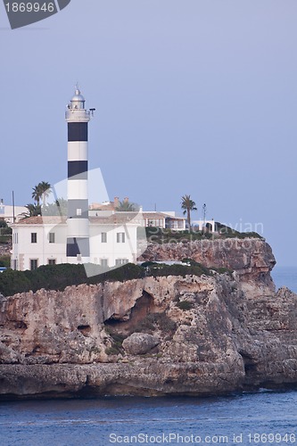 Image of white lighthouse on rocks in the sea ocean water sky blue